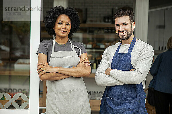 Bäckereibesitzer mit Schürze stehen mit verschränkten Armen