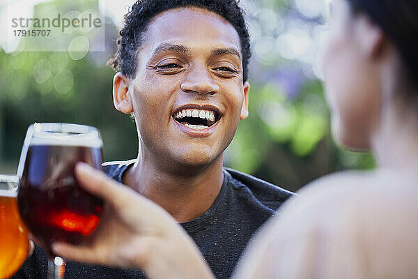 Fröhlicher lateinamerikanischer Mann  der sich beim Biertrinken mit Freunden amüsiert