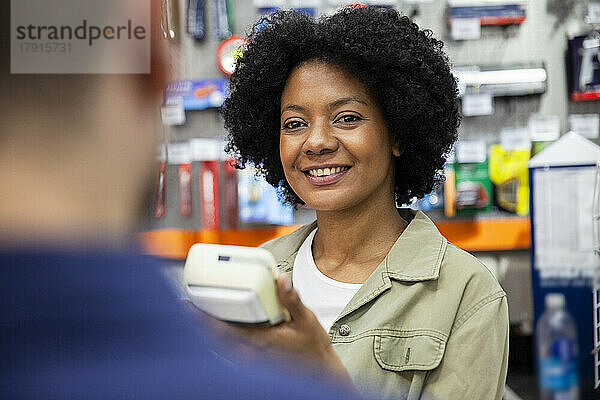 Eine afroamerikanische Eisenwarenverkäuferin bedient einen Kunden im Laden