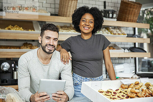 Bäckereibesitzer stehen hinter der Theke und halten ein digitales Tablet