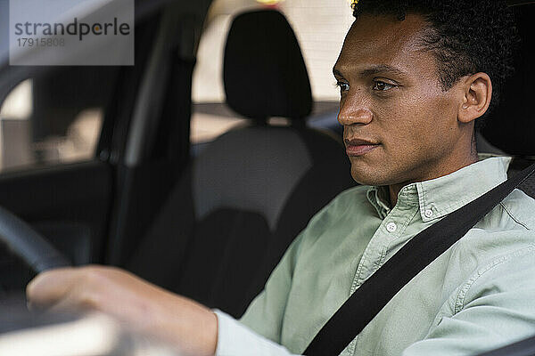 Porträt aus der Mitte des Fahrzeugs eines afroamerikanischen Geschäftsmanns  der mit seinem Auto zur Arbeit fährt