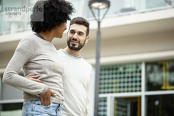 Glückliches junges erwachsenes Paar geht auf dem Bürgersteig