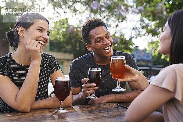 Eine bunt gemischte Gruppe fröhlicher Freunde  die bei der Happy Hour Craft Beer trinken