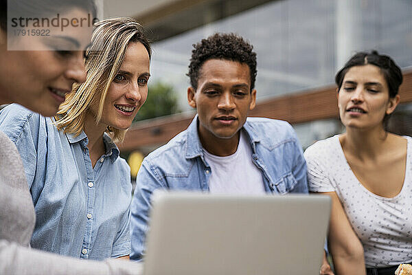 Verschiedene Gruppen von freiberuflichen Auftragnehmern  die im Freien auf einen Laptop-Bildschirm schauen