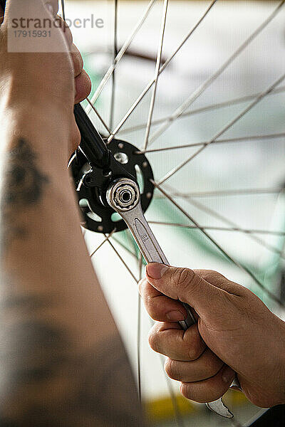 Nahaufnahme eines Fahrradmechanikers  der ein Rad mit einem Schraubenschlüssel einstellt