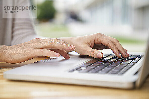 Nahaufnahme der Hände einer Frau  die auf einem Laptop tippen