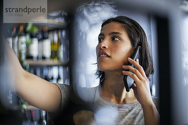 Angestellter einer Weinhandlung telefoniert mit seinem Smartphone