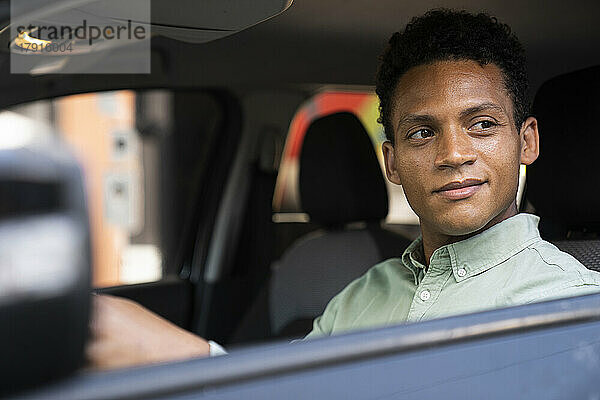 Mittelaufnahme eines gut aussehenden afroamerikanischen Geschäftsmannes  der mit seinem Auto zu seinem Büro fährt