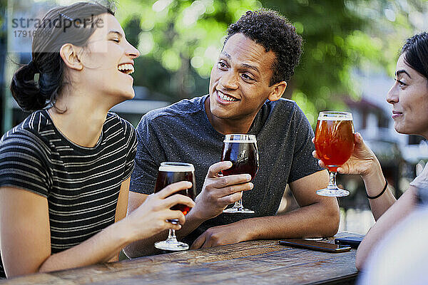 Junger lateinamerikanischer Mann trinkt Bier mit Freundinnen
