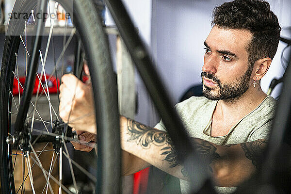 Junger erwachsener männlicher Mechaniker  der ein Fahrrad in einer Werkstatt repariert