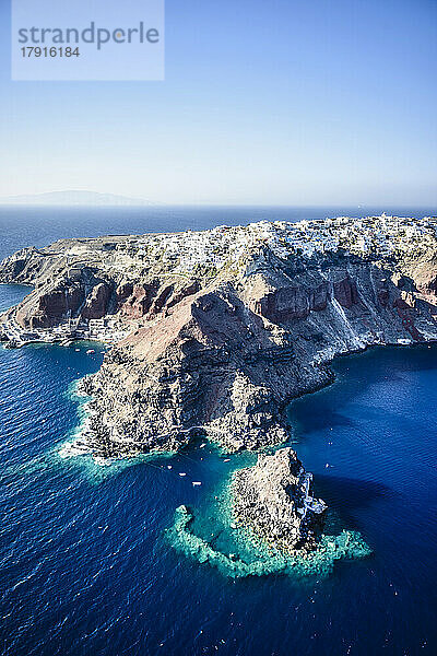 Luftaufnahme einer Insel im tiefblauen Meer der Ägäis  Felsformationen  weiß getünchte Häuser auf den Klippen.