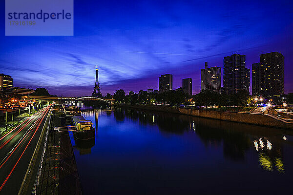 Ein Blick entlang der Seine bei Nacht  hohe Gebäude am Ufer  der Eiffelturm in der Ferne.