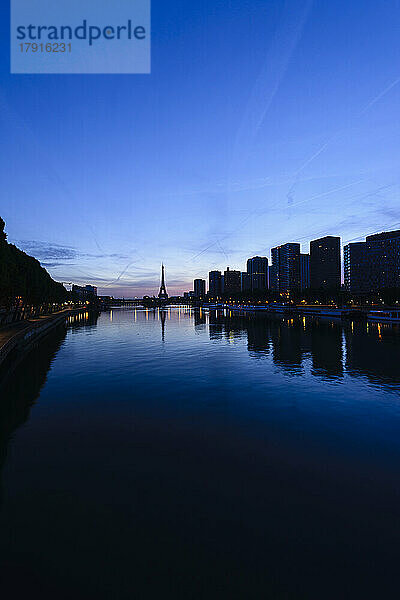 Ein Blick entlang der Seine bei Nacht  hohe Gebäude am Ufer  der Eiffelturm in der Ferne.