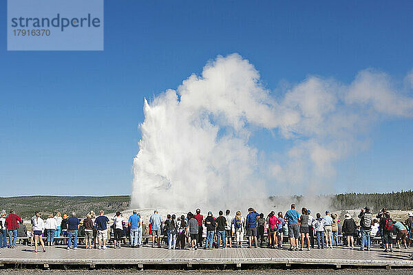 Rückansicht von Touristen mit Blick auf einen Geysir im Yellowstone Park.