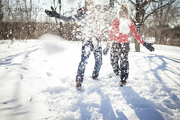 Ein Paar wirft im Park einen Schneeball auf die Kamera.