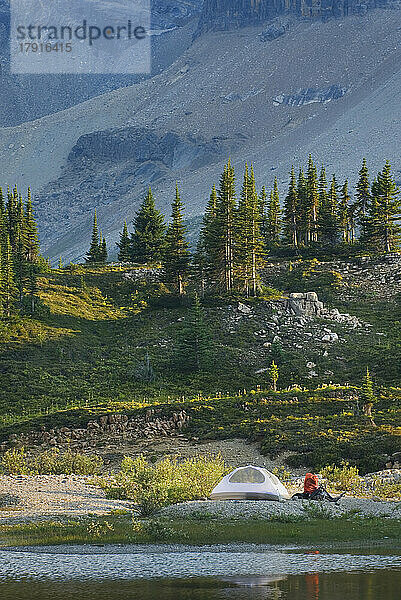 Ein kleines weißes Zelt und ein Rucksack am Ufer eines Sees im Yoho-Nationalpark.