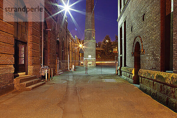 Eine Gasse in Georgetown  Seattle bei Nacht  renovierte Werftgebäude  ein Turm  Tore und Sicherheitsbeleuchtung.