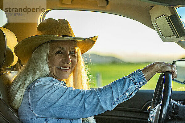 Ältere Frau im Auto mit Cowboyhut