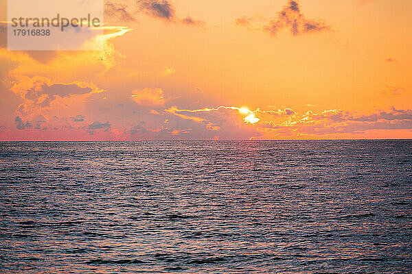 Dramatischer orangefarbener Himmel über dem Meer bei Sonnenaufgang