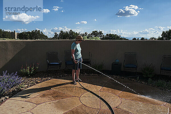 USA  New Mexico  Santa Fe  Frau wäscht Terrasse an sonnigem Tag