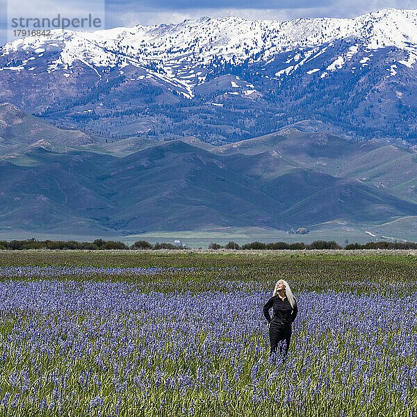 USA  Idaho  Fairfield  Frau steht im Feld blühender Camas-Lilien mit Soldier Mountain im Hintergrund