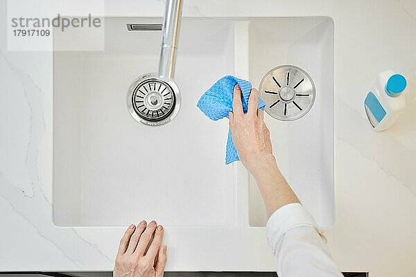 Draufsicht auf eine weibliche Hand mit Schwamm beim Waschen des Waschbeckens (Fokus auf eine Hand)