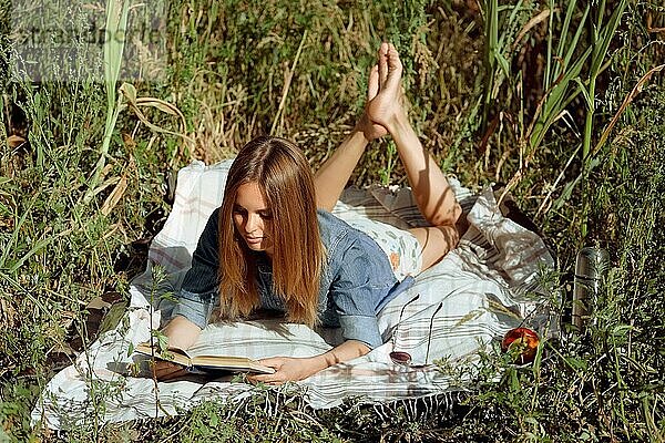 Hübsche Frau liest ein Buch  das auf einer Wiese liegt