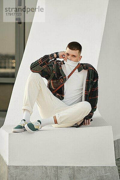Urbane Mode. Entspannter Mann in lockerer Kleidung sitzt auf der Straße