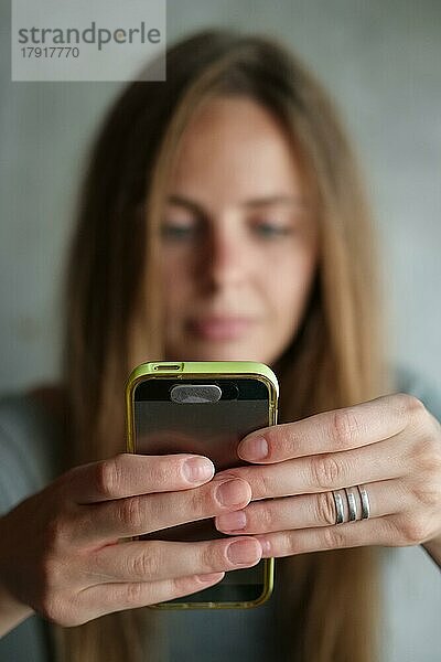 Weibliche Hände halten Telefon und tippen eine Nachricht (selektiver Fokus)