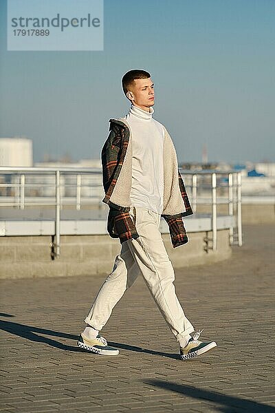 Urbane Mode. Junger Mann in lockerer Kleidung zu Fuß auf der Straße