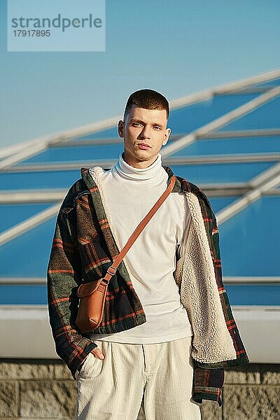 Urbane Mode. Junger Mann in lockerer Kleidung posiert auf der Straße