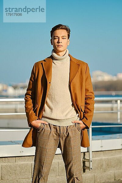 Frühling  Herbst Outfit. Straßenmode. Junger Mann in karierter Hose  Pullover und Wollmantel