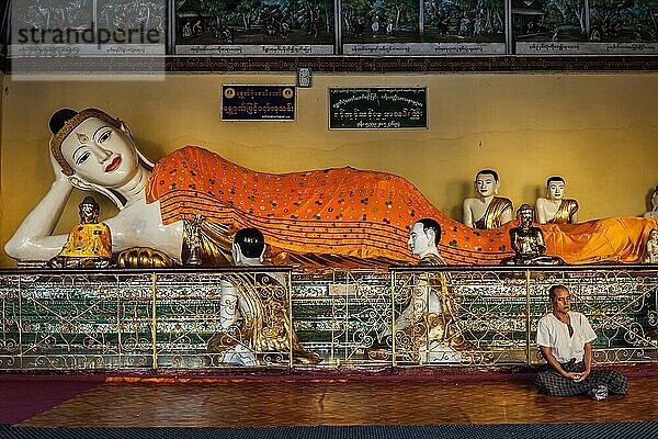 YANGON  MYANMAR  3. JANUAR 2014: Mann meditiert in der Nähe der Statue des liegenden Buddhas in der Shwedagon Paya Pagode