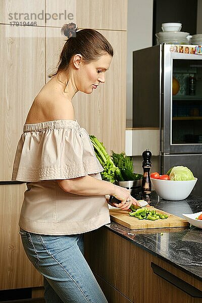 Werdende Mutter bei der Zubereitung gesunder Speisen zu Hause. Konzept der gesunden Lebensweise