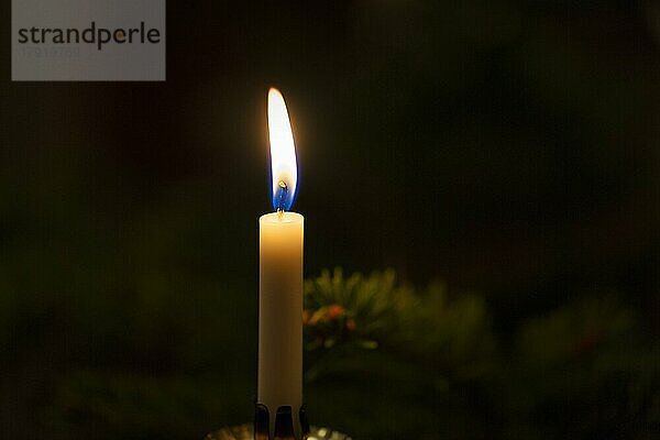 Schwaches Licht einer einzelnen Kerze in der Dunkelheit  Weihnachtsbeleuchtung  Symbolbild Strom sparen  Stromausfall  Blackout