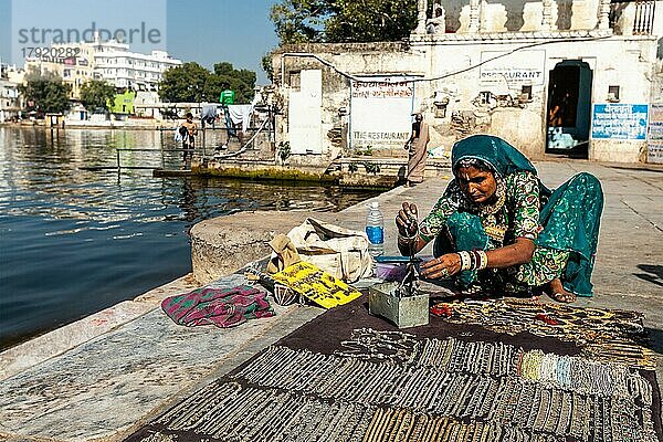 UDAIPUR  INDIEN  24. NOVEMBER 2012: Eine Straßenverkäuferin in traditioneller Kleidung verkauft Schmuck am Ghat des Pichola-Sees. Udaipur  Rajasthan  Indien  Asien