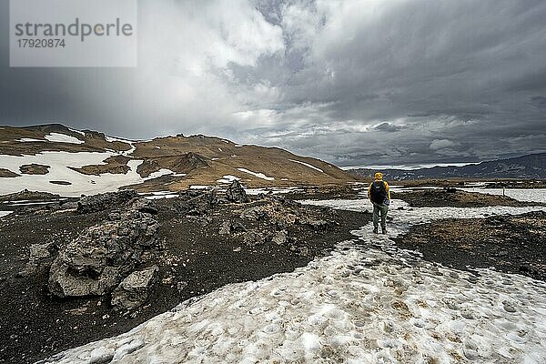 Wanderer in schneebedeckter Vulkanlandschaft mit vulkanischem Sand und versteinerter Lava  Krater des Vulkans Askja  isländisches Hochland  Island  Europa