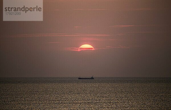 Frachtschiff im Mittelmeer unter der Abendsonne  fotografiert vom Strand bei Tarragona  Katalonien  Spanien  Europa