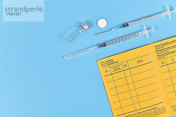Vaccine Konzept mit Spritze  Fläschchen und gelben internationalen Zertifikat der Impfung auf blauem Hintergrund mit Kopie Raum