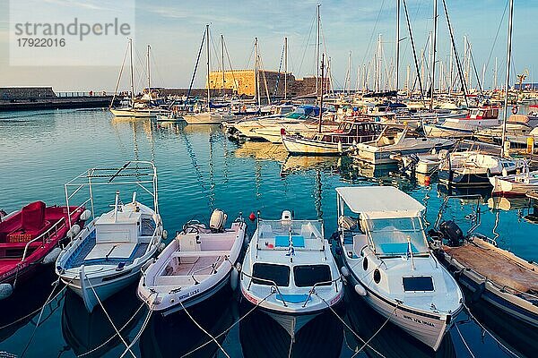 HERAKLION  GRIECHENLAND  20. MAI 2019: Die venezianische Festung in Heraklion  der Hauptstadt der Insel Kreta  und vertäute Fischerboote bei Sonnenuntergang