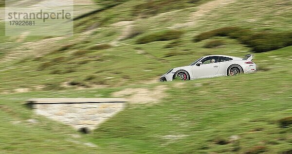 Foto mit Geschwindigkeitseffekt von Sportwagen Porsche GT3 fährt auf Bergstraße in Hocchalpen  Departement Auvergne-Rhône-Alpes  Frankreich  Europa