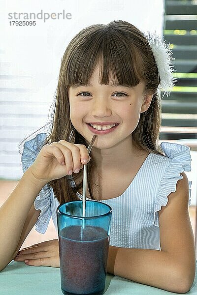Achtjähriges Mädchen trinkt einen Smoothie aus einem Metallstrohhalm