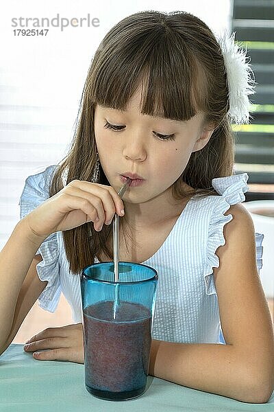 Achtjähriges Mädchen trinkt aus einem Metallstrohhalm