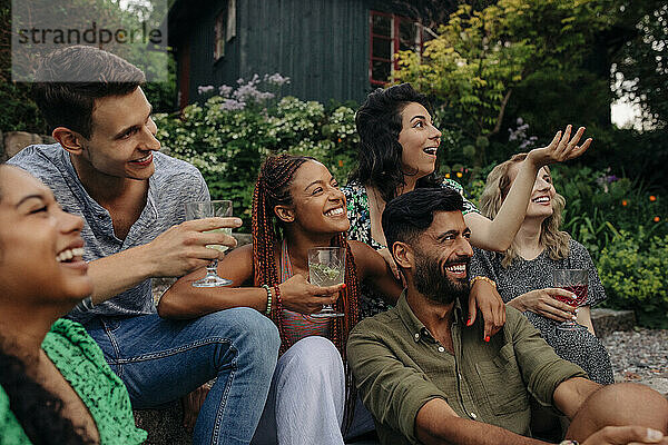 Glückliche männliche und weibliche Freunde mit Getränken  die sich auf einer Gartenparty amüsieren