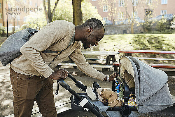 Lächelnder Vater sieht seinen Sohn im Kinderwagen an