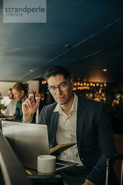 Porträt eines Geschäftsmannes mit Brille  der mit einem Laptop in einem Hotel sitzt