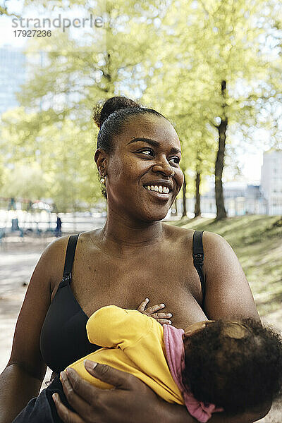 Glückliche Mutter  die ihre Tochter im Park stillt