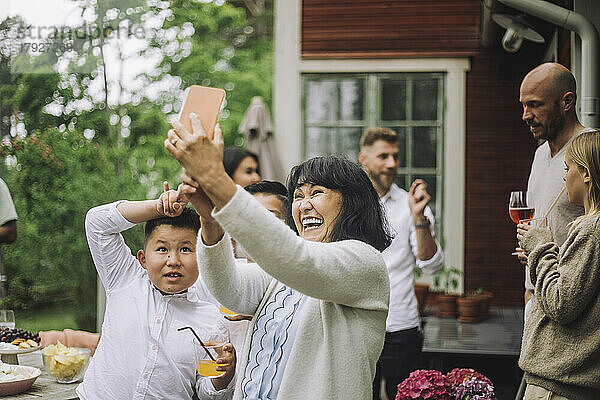 Glückliche Großmutter nimmt Selfie durch Smartphone mit Enkelkindern auf Party