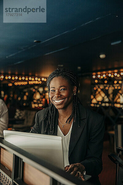 Porträt einer glücklichen jungen Berufstätigen mit Laptop im Hotel