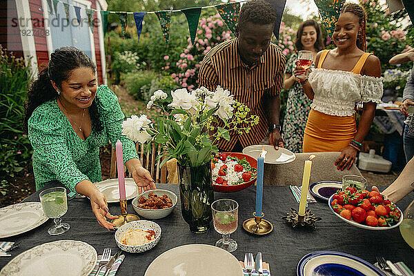 Männliche und weibliche Freunde bauen einen Tisch während einer Gartenparty auf